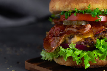 Macro shot of homemade fresh beef burger on wooden board on dark background with copy space