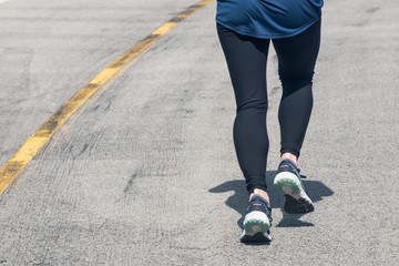 Legs of a runner jogging on asphalt road in sport shoes. 