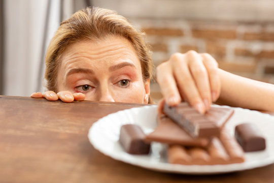 Dark-eyed Mature Woman With Allergy Taking Piece Of Chocolate