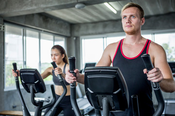 Young couple sport exercise with elliptical machine in gym . fitness man and woman workout together ,training,