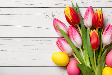 Fresh colorful tulips and easter eggs on wooden background