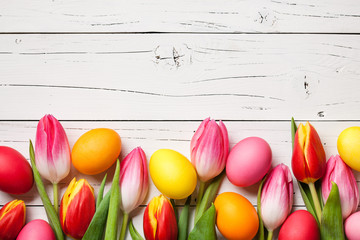 Fresh colorful tulips and easter eggs on wooden background
