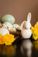 Small white rabbit figurine with easter eggs and narcissus