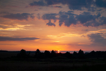 View of a Beautiful Sunset and Sky with dramatic clouds over a Silhouetted Land Horizont.