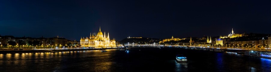 Fototapeta na wymiar Panoramic night view of the Danube River as it passes through Budapest along with the Parliament, the Cathedral, the Fishermen's Bastion, the Buda Castle-Palace, the Chain Bridge and the Fortress,