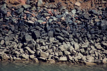 Dark rocks at the beach background. Stones texture