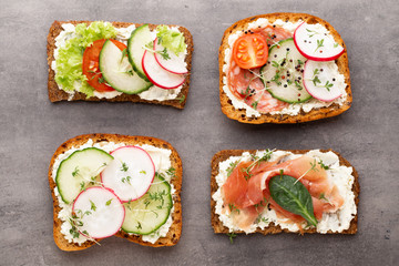 Sandwich with cereals bread and salami on dark marble background.