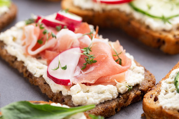 Sandwich with cereals bread and salami on dark marble background.