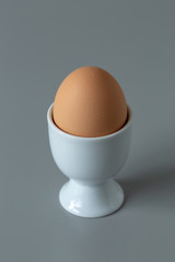 Egg plain single in white egg cup minimal simple design on grey background
