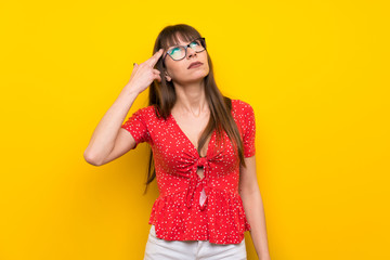 Young woman over yellow wall with problems making suicide gesture