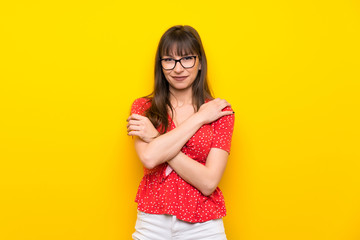 Young woman over yellow wall with glasses and happy
