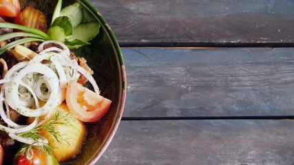 Kazan-kebab - fried meat and potatoes. Central Asian cuisine. Rotates on a wooden background. Top view with the copy space for your text.