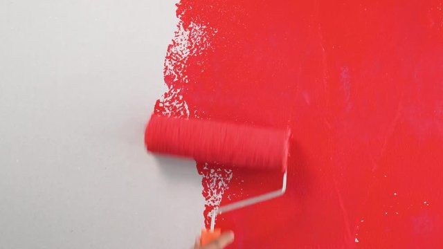 Footage roller for painting walls with red paint on the wall in the house