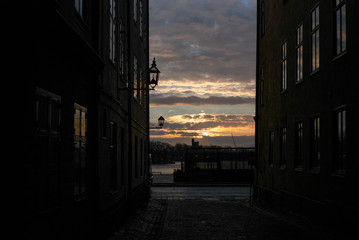 Sunrise sun filtering through on the old cobbled narrow street with colorful houses in Stockholm in the morning - 1