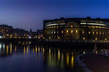 Fototapeta na wymiar The Swedish Parliament building reflecting in the water at sunset in winter in Stockholm