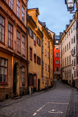 Fototapeta na wymiar Old cobbled narrow street with coilorful houses in Stockholm in the morning - 1