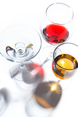 Glass glasses with drinks of different colors on a white background. Top view. The concept of an alcoholic cocktail.