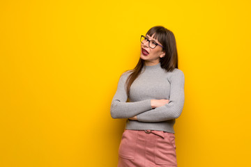 Obraz premium Woman with glasses over yellow wall with confuse face expression while bites lip