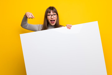 Woman with glasses over yellow wall holding a placard for insert a concept