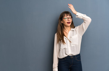 Woman with glasses over blue wall has just realized something and has intending the solution