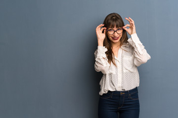 Woman with glasses over blue wall with glasses and surprised