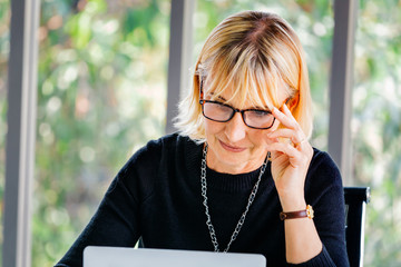 40s senior Caucasian businesswoman concentrating and staring at computer laptop in office...