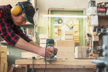 Worker grinds the wood box of angular grinding machine. Profession, carpentry and woodwork concept.