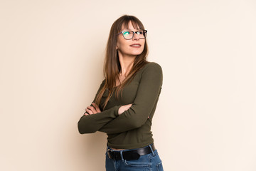 Young woman on ocher background with arms crossed and happy