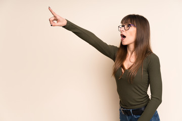 Young woman on ocher background pointing away