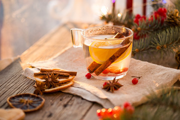 Winter theme. Christmas tea with spices, cup of tea with orange, cinnamon, anise, cookies in a shape of star, pepper and gray scarf on wooden background. Flat lay, View from above. Copy space for text