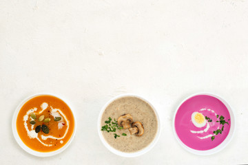 Variety of colorful vegetables cream soups on white background. Champignon cream soup.Pumpkin...