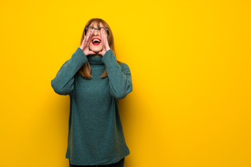 Woman with glasses over yellow wall shouting and announcing something