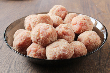 full bowl of raw meatballs on wooden table