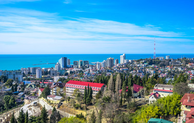 Blue coast of Black Sea in Sochi with houses under summer cloudy sky