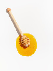Wooden spoon for honey and spilled honey on a white background. Top view.