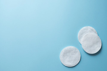 Clean white cotton stack of disk for beauty face hygiene with selective focus on blue neutral background. Cosmetic softness pure sponge for makeup remover. Sterile cleanliness facial sponges