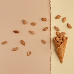 Waffle ice cream cones filled with almond nuts on a paper background. Top view. Copy space. Minimalistic concept.