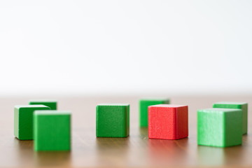 green wooden building blocks with one red block beside each other