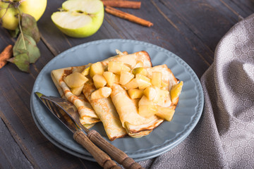 Crepes with apple filling and caramel sauce on a plate close-up, selective focus.
