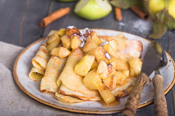 Crepes with apple filling and caramel sauce on a plate close-up, selective focus.