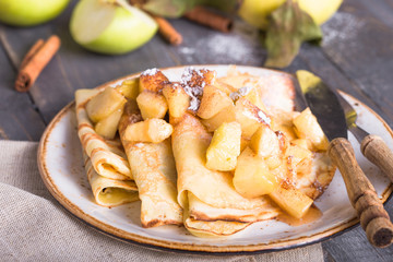 Crepes with apple filling and caramel sauce on a plate close-up, selective focus.