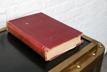 Old book in a red cover on the table.