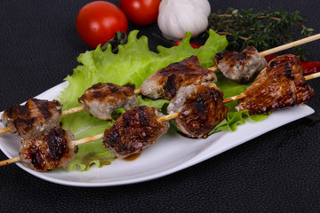 Pork kebab skewers in the plate with salad leaves and tomatoes