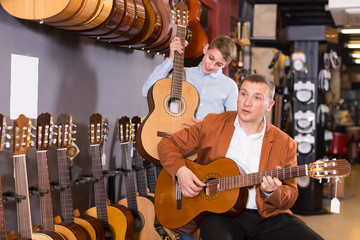 Young seller showing guitar to boy client