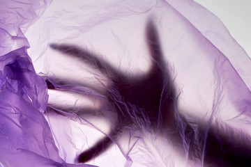 Dead hand in plastic bag. Murder concept. Puple color background.