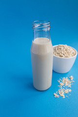 Oat milk in the glass  bottle  on the blue background.Healthy drink.