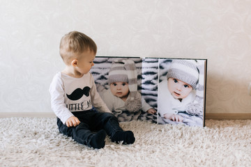 Cute baby sitting on the background of a large stylish photo book with your photos