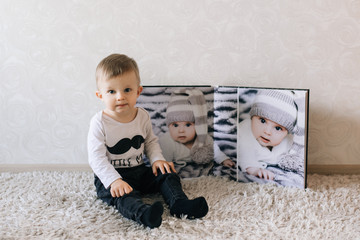 Naklejka premium Cute baby sitting on the background of a large stylish photo book with your photos