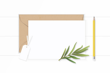Flat lay top view elegant white composition letter kraft paper envelope yellow pencil tarragon leaf and tag on wooden background