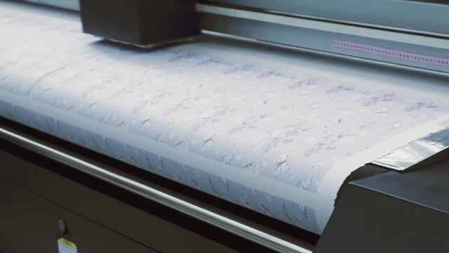 Industrial printing on woven material; modern digital inkjet printer puts a blue pattern picture on a cloth canvas